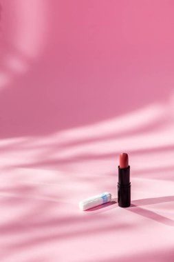 Periyotlarda hijyeni korumak için tampon. Kadınların sağlıklarına ve adet dönemlerinde rahat günlere dikkat edin. Beyaz pamuklu tampon ve pembe arka planda güneş ışığı üzerine ruj..