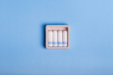 Dönem boyunca hijyeni korumak için tamponlar. Dönem boyunca rahat günler. Periyodlarda kadın sağlığına dikkat edin. Mavi arka planda beyaz pamuklu tamponlar. Kadın hijyeni..