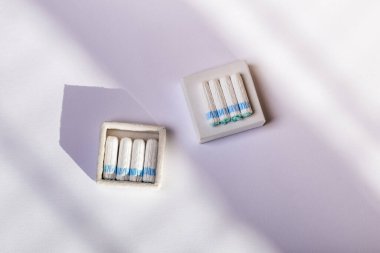 Regl sırasında hijyeni korumak için kadın tamponları. Yukarıdan beyaz arka planda güneş ışığında hijyenik tamponlar. Regl sırasında rahatlık ve koruma. Kadın hijyeni ve sağlığı..