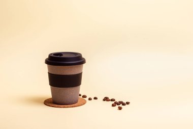 Paket kahve. Kahve ya da çay için tekrar kullanılabilir çevre dostu fincan, bej arka planda kahve çekirdekleri. Paket kahve. Metin için yer.