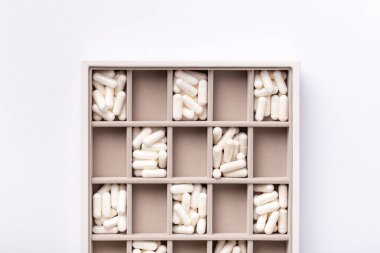 Beyaz arka plandaki beyaz vitamin kapsülleri kutunun içinde. Vitaminler ve besin takviyeleri.