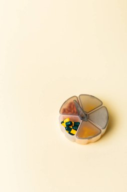 Bej arka planda yuvarlak hap organizatörü. Vitaminler ve mineraller düzenleyicide.