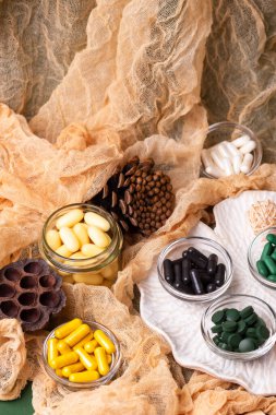 Birçok renkli vitamin ve mineral, beslenme takviyeleri, bağışıklık sistemini geliştirmek ve insan sağlığını desteklemek için çeşitli haplar ve tabletler. Yukarıdan gelen vitaminler ve besin takviyeleri koyu yeşil arka planda. Kırsal stil, üst görünüm. Sağlıklı yaşam.
