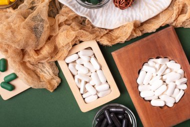 Birçok renkli vitamin ve mineral, beslenme takviyeleri, bağışıklık sistemini geliştirmek ve insan sağlığını desteklemek için çeşitli haplar ve tabletler. Koyu yeşil arka planda yukarıdaki kavanozlarda vitaminler.
