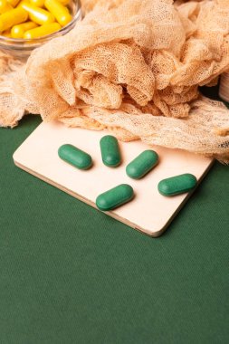 Birçok renkli vitamin ve mineral, beslenme takviyeleri, bağışıklık sistemini geliştirmek ve insan sağlığını desteklemek için çeşitli haplar ve tabletler. Koyu yeşil arka planda yukarıdaki kavanozlarda vitaminler.
