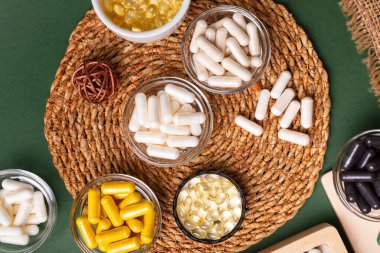 Birçok renkli vitamin ve mineral, beslenme takviyeleri, bağışıklık sistemini geliştirmek ve insan sağlığını desteklemek için çeşitli haplar ve tabletler. Yukarıdan gelen vitaminler ve besin takviyeleri koyu yeşil arka planda. Kırsal stil, üst görünüm. Sağlıklı yaşam.
