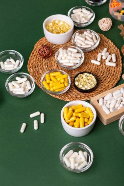 Birçok renkli vitamin ve mineral, beslenme takviyeleri, bağışıklık sistemini geliştirmek ve insan sağlığını desteklemek için çeşitli haplar ve tabletler. Yukarıdan gelen vitaminler ve besin takviyeleri koyu yeşil arka planda. Kırsal stil, üst görünüm. Sağlıklı yaşam.