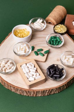 Birçok renkli vitamin ve mineral, beslenme takviyeleri, bağışıklık sistemini geliştirmek ve insan sağlığını desteklemek için çeşitli haplar ve tabletler. Koyu yeşil arka planda yukarıdaki kavanozlarda vitaminler.