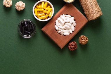 Birçok renkli vitamin ve mineral, beslenme takviyeleri, bağışıklık sistemini geliştirmek ve insan sağlığını desteklemek için çeşitli haplar ve tabletler. Koyu yeşil arka planda yukarıdaki kavanozlarda vitaminler.