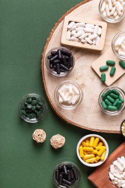 Birçok renkli vitamin ve mineral, beslenme takviyeleri, bağışıklık sistemini geliştirmek ve insan sağlığını desteklemek için çeşitli haplar ve tabletler. Koyu yeşil arka planda yukarıdaki kavanozlarda vitaminler.