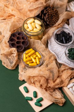 Birçok renkli vitamin ve mineral, beslenme takviyeleri, bağışıklık sistemini geliştirmek ve insan sağlığını desteklemek için çeşitli haplar ve tabletler. Yukarıdan gelen vitaminler ve besin takviyeleri koyu yeşil arka planda. Kırsal stil, üst görünüm. Sağlıklı yaşam.