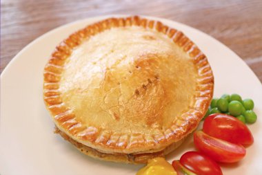 Bir tabak taze pişmiş altın kahverengi etli turta.