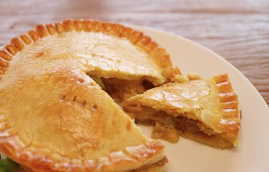 Beyaz bir tabakta taze pişmiş, kahverengi etli börek.