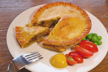 Tahta Masa üzerinde servis edilen nefis bir tabak altın sarısı etli börek.