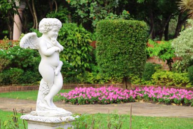 An adorable cupid sculpture in the flowering garden