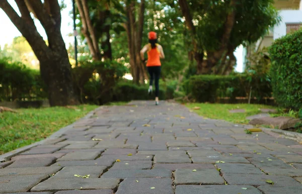Closeup of paving path in a garden with blurry jogging woman in the backdrop