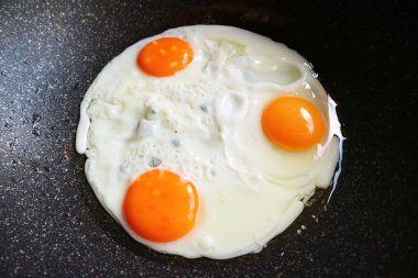 Tavada kızartılan üç tavuk yumurtası.