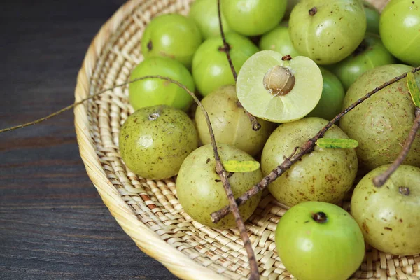 Heap of Fresh Indian Gooseberries or Amla in a Basket on Black Wooden Table