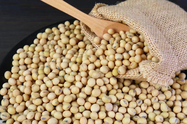 stock image Dried Soybeans Scattered from Burlap Bag on to Black Wooden Table