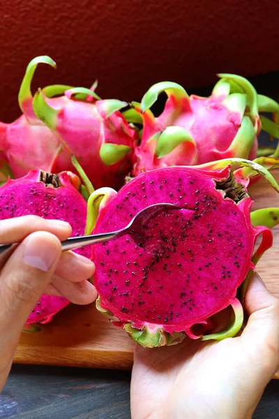 Hand Scooping Delectable Hot Pink Flesh of Red Dragon Fruits or Pink Pitaya with a Spoon