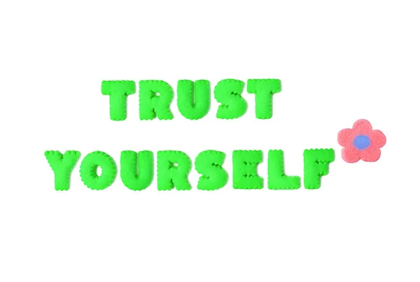 ホワイトバックグラウンドのライムグリーンアルファベットクッキーで綴られたTrust Yourselfのテキスト — ストック写真