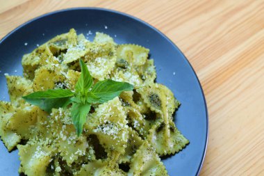 Tahta masada servis edilen Pesto sosunda nefis papyonlu makarna veya Farfalle.