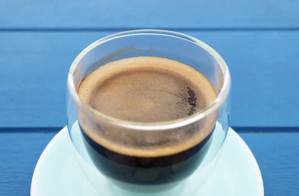 Eingeschlossen Ein Glas Heißen Schwarzen Kaffee Isoliert Auf Blauem Holztisch — Stockfoto