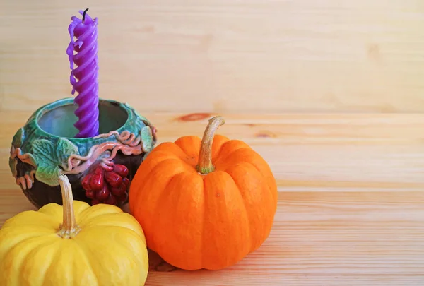 Autumn decoration of yellow and orange ripe pumpkins with a candle holder on wooden table