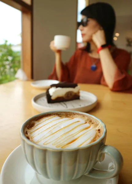 Zbliżenie Filiżanka Gorącego Karmelu Macchiato Kobietą Pijącą Kawę Tle — Zdjęcie stockowe