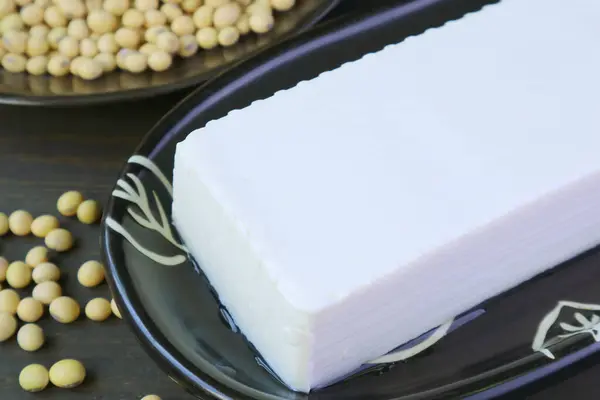 Closeup of a Soft Tofu Bean Curd with Blurry Dried Soybeans Pile in Background