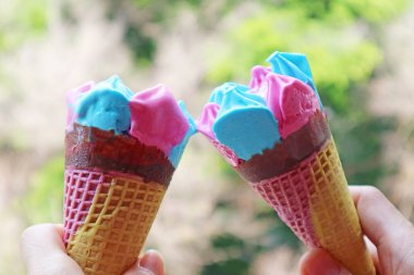 İki adet Pembe ve Mavi Dondurma Külahı Yeşil Yapraklar Arkaplanına Vuruyor