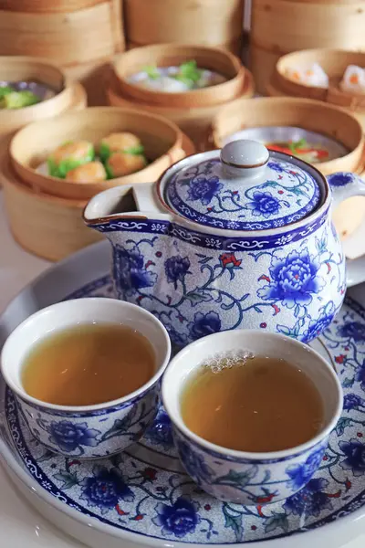 Two Cups of Hot Chinese Oolong Tea with Blurry Assorted Dim Sum Dishes in Background