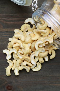 Cam kavanozdan ahşap masaya saçılmış kurumuş fındık yığını.