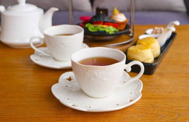 İki fincan sıcak çay, bulanık çörekler ve öğleden sonra çaylı çörekler.