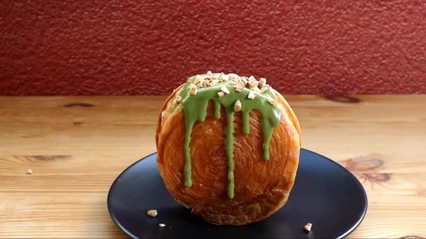 Filmación Croissant Supremo Cubierto Con Nueces Picadas Salsa Verde Matcha — Vídeo de stock