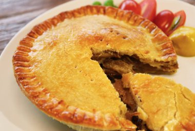 Ağız sulandıran taze pişmiş etli böreğin beyaz bir tabakta yakınlaşması.