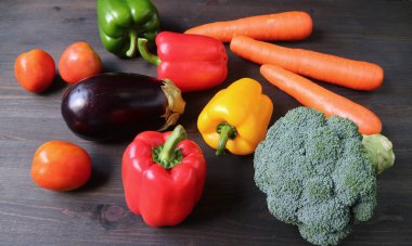 Çok renkli taze sebzeler, siyah ahşap arka plana saçılmış.