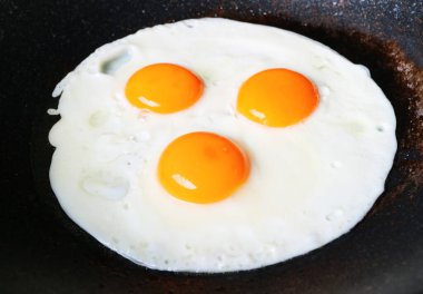 Tavada kızartılan üç tavuk yumurtasının yakın çekimi.