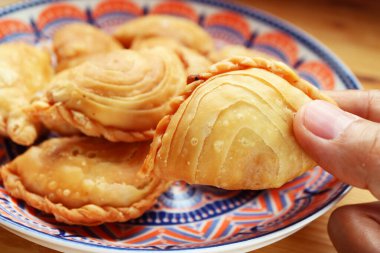 Closeup of Hand Picking a Thai Curry Puff, Popular Snack Similar to Empanadas and Samosa clipart