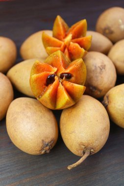 Beautifully Cut Sapodilla Fruit on Heap of Whole Fruits clipart