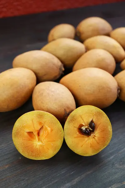 stock image Closeup of Cut Sapodilla Fruit with Heap of Whole Fruits in the Backdrop