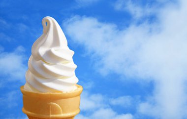 Ağzını sulandıran vanilyalı dondurma külahına karşı canlı mavi gökyüzü.