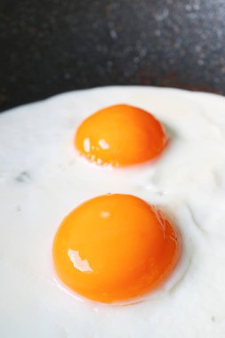 Bir çift güneşli tarafı yakın çekim tavada kızartılan yumurtalar.