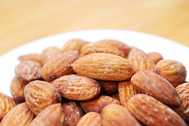 Badem çekirdeği dolu beyaz tabak Tahta Masa 'da izole edildi