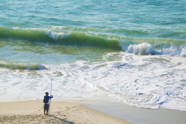 Dalgalarda elinde olta olan insanlar sahile düştü.