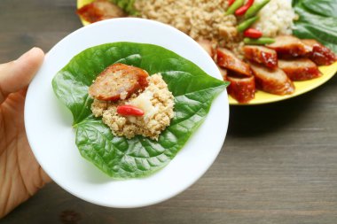 One Bite of Sai Krok-Planaem, Thai Style Grilled Pork Sausages with Shredded Fish and Pork Wrapped in Fresh Wild Betel Leaf clipart