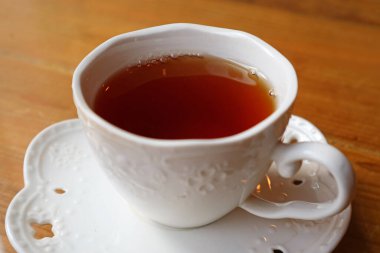 Tahta masada servis edilen bir fincan sıcak çayın yakın çekimi.