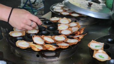 Satıcının popüler Tayland hindistancevizi krepi Kanom Krok 'u servis etmeye hazır olduğunda tavadan çıkardığı görüntüler.