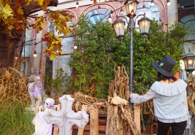 Woman Entering the Garden with Spooky Halloween Decoration with Tombstones and Skeleton clipart