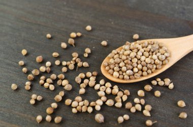 Bir kaşık dolusu kurutulmuş kişniş tohumları kara tahta arka planda